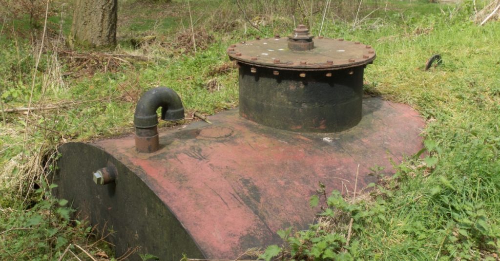 rusted oil tank partially in ground, concept of Storage Tank Sampling Requirements for NJ Businesses